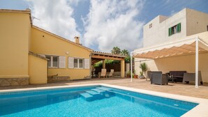 A swimming pool with a covered patio area, outdoor furniture, and a building with a yellow facade. - Holiday house with private pool only 200m to the beach, Cala Ratjada, Mallorca (Cala Ratjada)