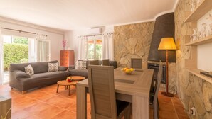 A living room with a sofa, dining table, chairs, a fireplace, and a stone wall. - Holiday house with private pool only 200m to the beach, Cala Ratjada, Mallorca (Cala Ratjada)