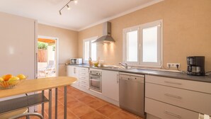 A modern kitchen with white cabinets, stainless steel appliances, and a window with blinds. - Holiday house with private pool only 200m to the beach, Cala Ratjada, Mallorca (Cala Ratjada)