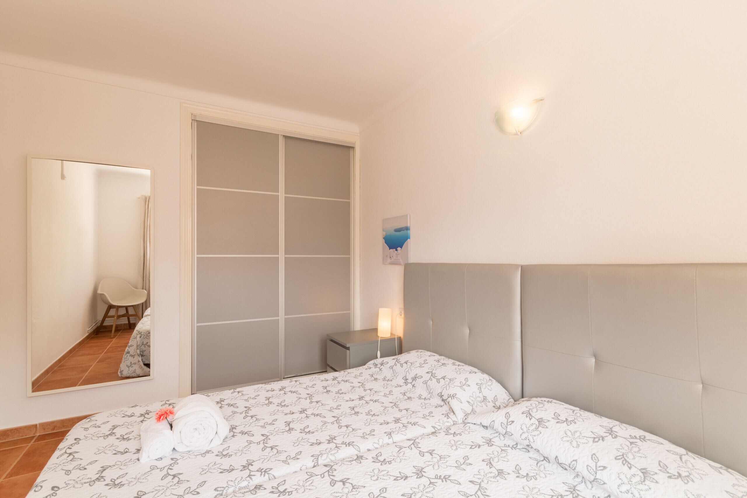 Une chambre à coucher comprenant un lit, une table de chevet, un miroir et une porte coulissante.