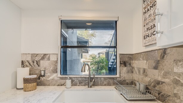 Una cocina moderna con un ventanal amplio, encimeras de mármol y un lavabo empotrado.