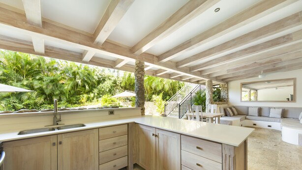 A modern kitchen with a large island, wooden cabinets, and a stone countertop. - Luxurious Ganesh Villa (Nicoya)
