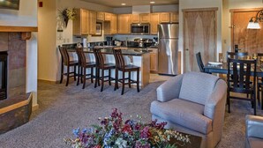 A modern kitchen with wooden cabinets, stainless steel appliances, and a dining area with a gray sofa and chairs. - Ski-In/Ski-Out Luxury at Grand Timber Lodge – Breckenridge, CO (Breckenridge)