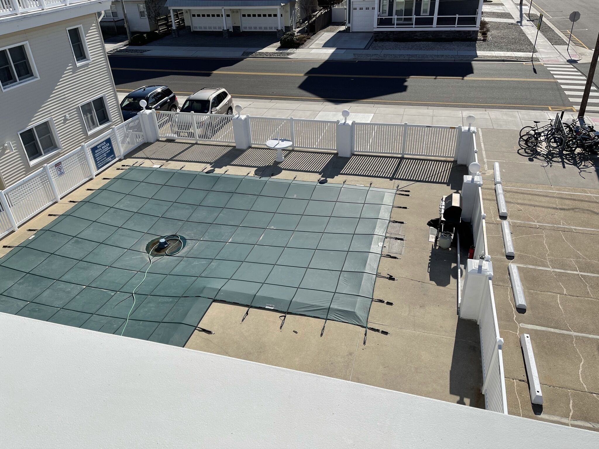 A rooftop with a green roof, white railings, and a view of the street below.