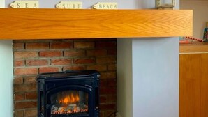 Una llar de foc amb una paret de maó, un televisor a la part superior i prestatges de fusta amb les paraules 'SEA', 'SURF', 'BEACH'.
