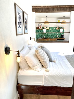 Cozy retreat with a neatly made bed, wall-mounted light, and shelf displaying a coffee maker and decorative items.