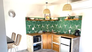 A compact kitchen with a microwave, coffee maker, and a sink. There are wicker chairs and a small dining table. - Loreto80-NEW Studio Palma, in downtown by beach (Loreto)