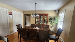 A dining room with a wooden table and chairs, a chandelier, a cabinet with glass doors, and a potted plant. - Skiing, snowshoeing, snowmobile/ATV trails, hunting, hiking and kayaking (Rumford)