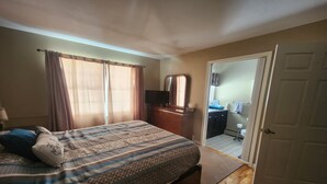A bedroom with a large bed, a dresser, a mirror, and a door leading to a bathroom. - Skiing, snowshoeing, snowmobile/ATV trails, hunting, hiking and kayaking (Rumford)
