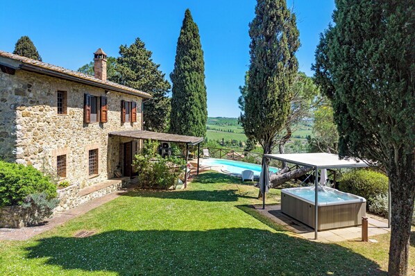 A stone house with a swimming pool, a hot tub, and a pergola.