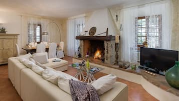 Ein Wohnzimmer mit Kamin, Sofa, Fernseher und Essbereich.