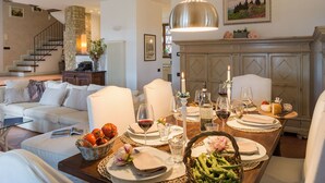 Un comedor con una mesa dispuesta para una comida, una chimenea y una escalera que lleva a un piso superior.