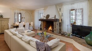 Una sala de estar con chimenea, sofá, televisión y un comedor con sillas y mesa.