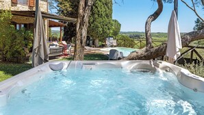Un jacuzzi con vista despejada del paisaje circundante, incluyendo un árbol y un edificio con terraza.