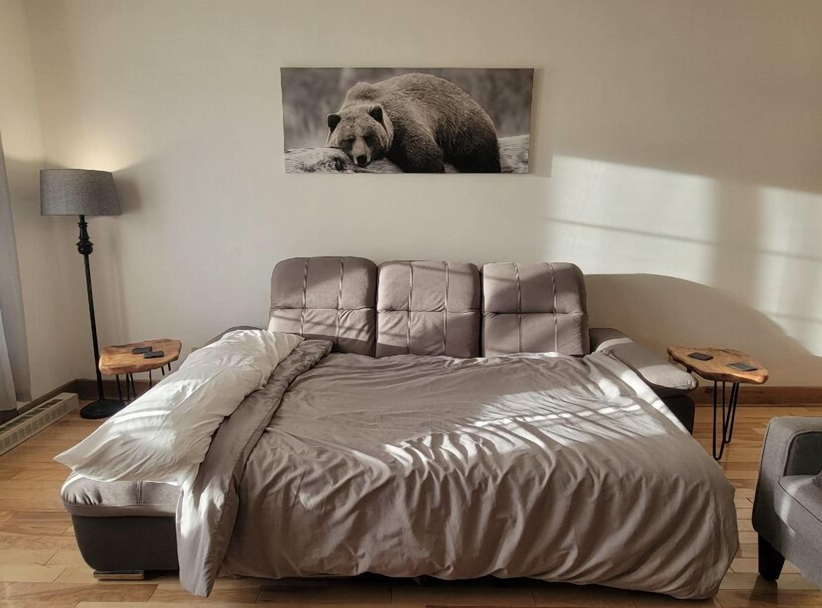 Une chambre à coucher avec un grand lit, une table de chevet, une lampe et un tableau accroché au mur.