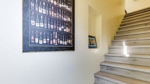 Un escalier avec des marches en bois et un porte-bouteilles fixé au mur, contenant différentes bouteilles de vin.