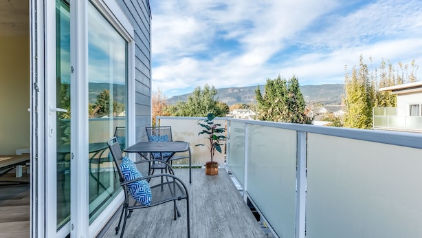 Un balcon avec une table et des chaises, un pot de fleurs et une vue sur le paysage environnant.