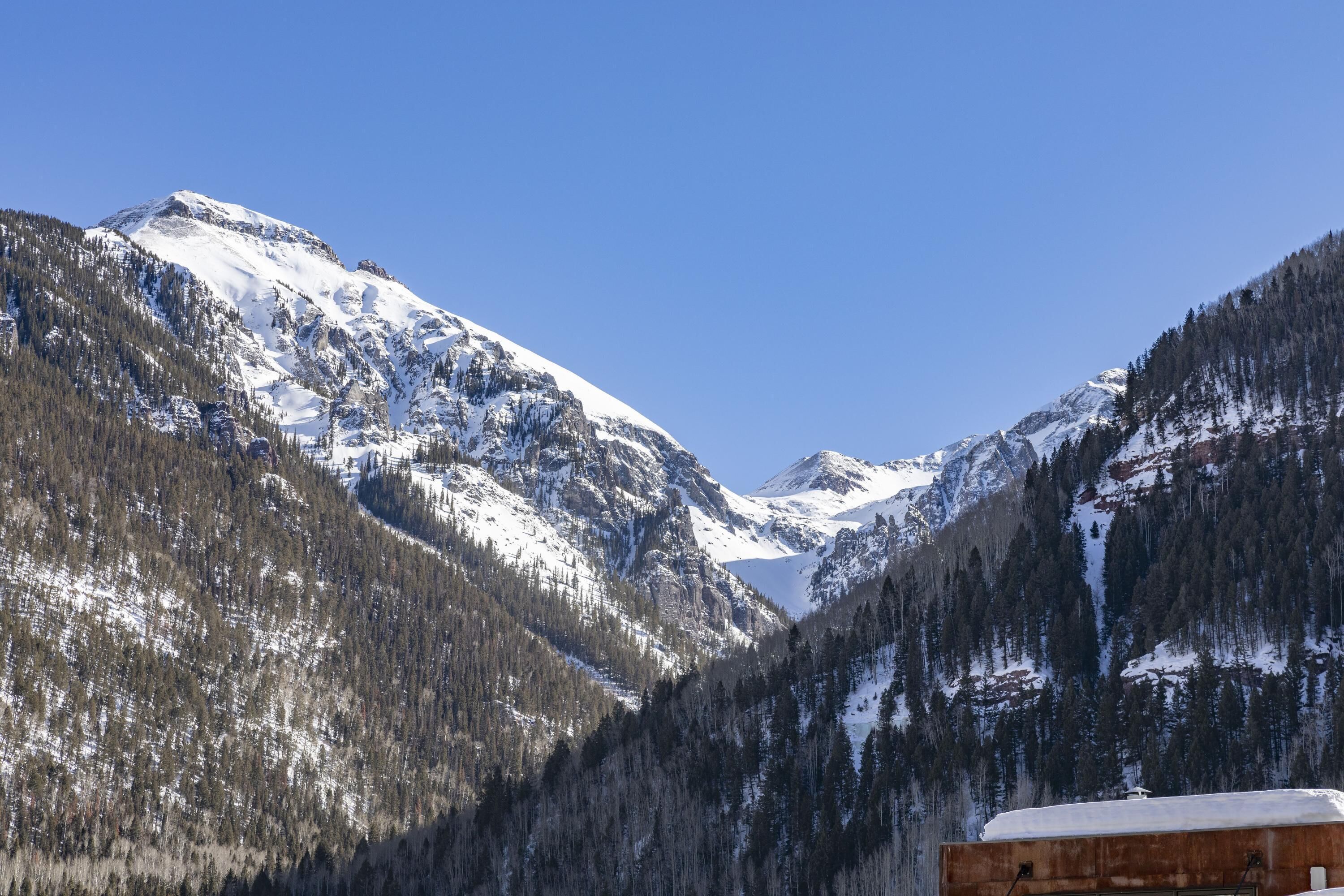A mountainous landscape with snow-covered peaks and dense forests.