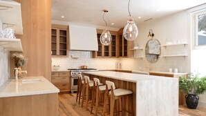 A modern kitchen with wooden cabinets, a marble island, bar stools, and pendant lighting. - Splendid Home in the Heart of Telluride Town (Telluride)