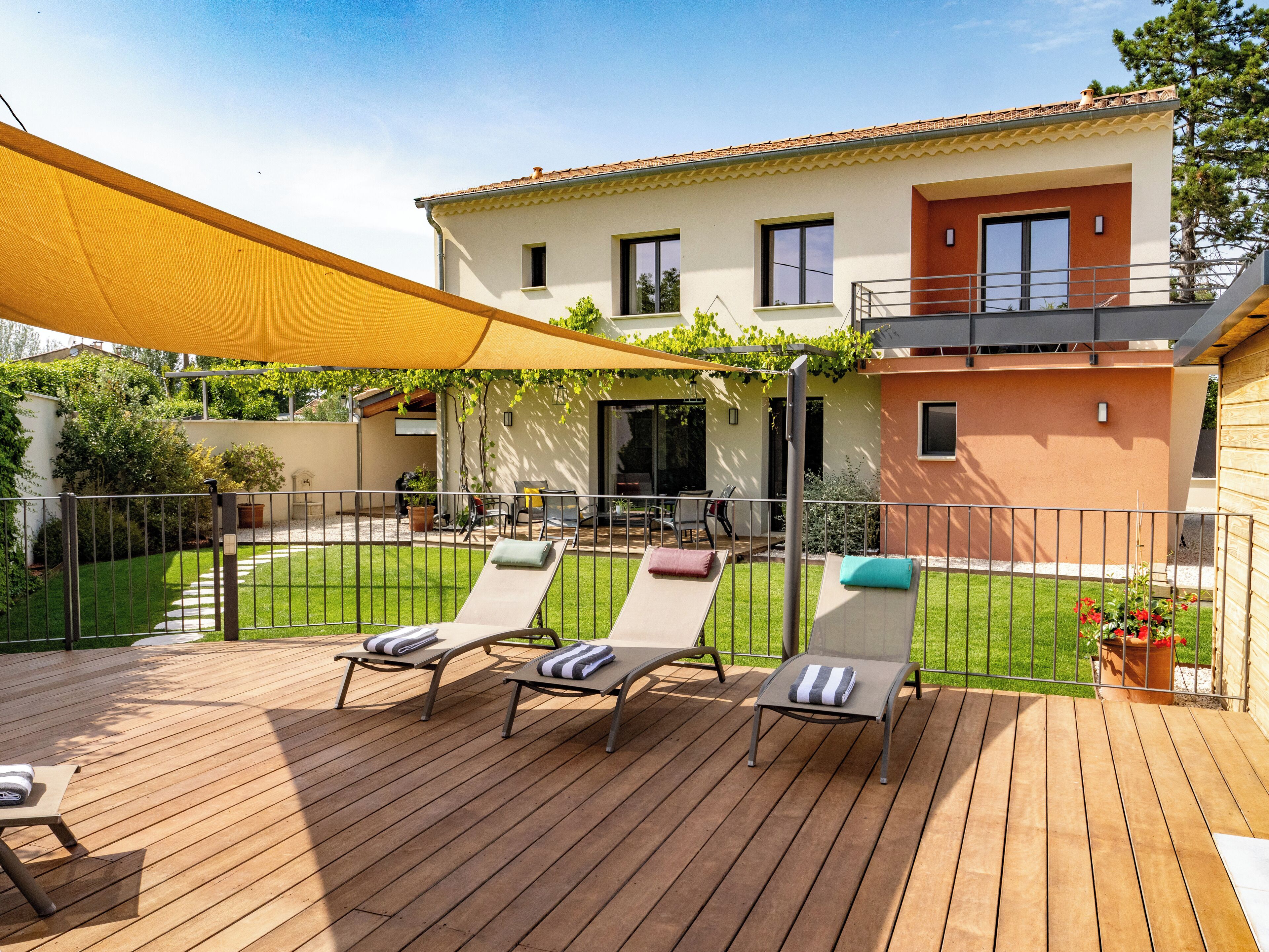 Une terrasse en bois avec des chaises longues et un auvent jaune.