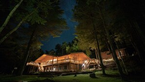 A cabin with a wooden exterior, a balcony, and a staircase leading to the upper level.
