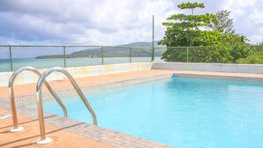 A swimming pool with a view of the sea and hills in the background. - Rica Vista Beach Cottages (Boscobel)