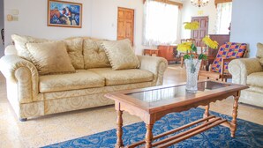A living room with a beige sofa, a glass coffee table, and a blue patterned rug. - Rica Vista Beach Cottages (Boscobel)