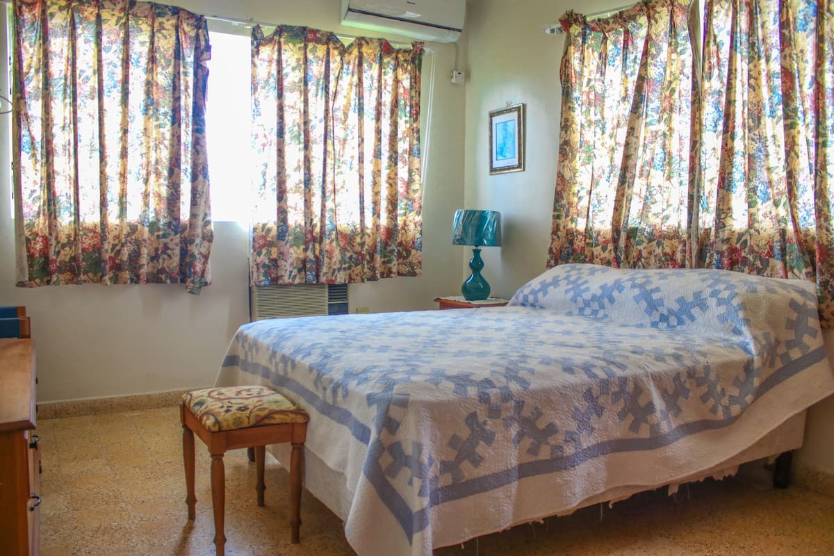 A bedroom with a bed, a chair, a lamp, and curtains.