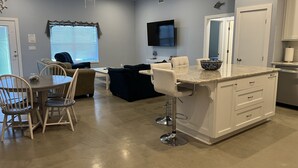 A modern kitchen with a central island, bar stools, and a dining area with chairs and a table. - Perfect for fishermen and families for your stay in Port O'Connor! (Port O'Connor)