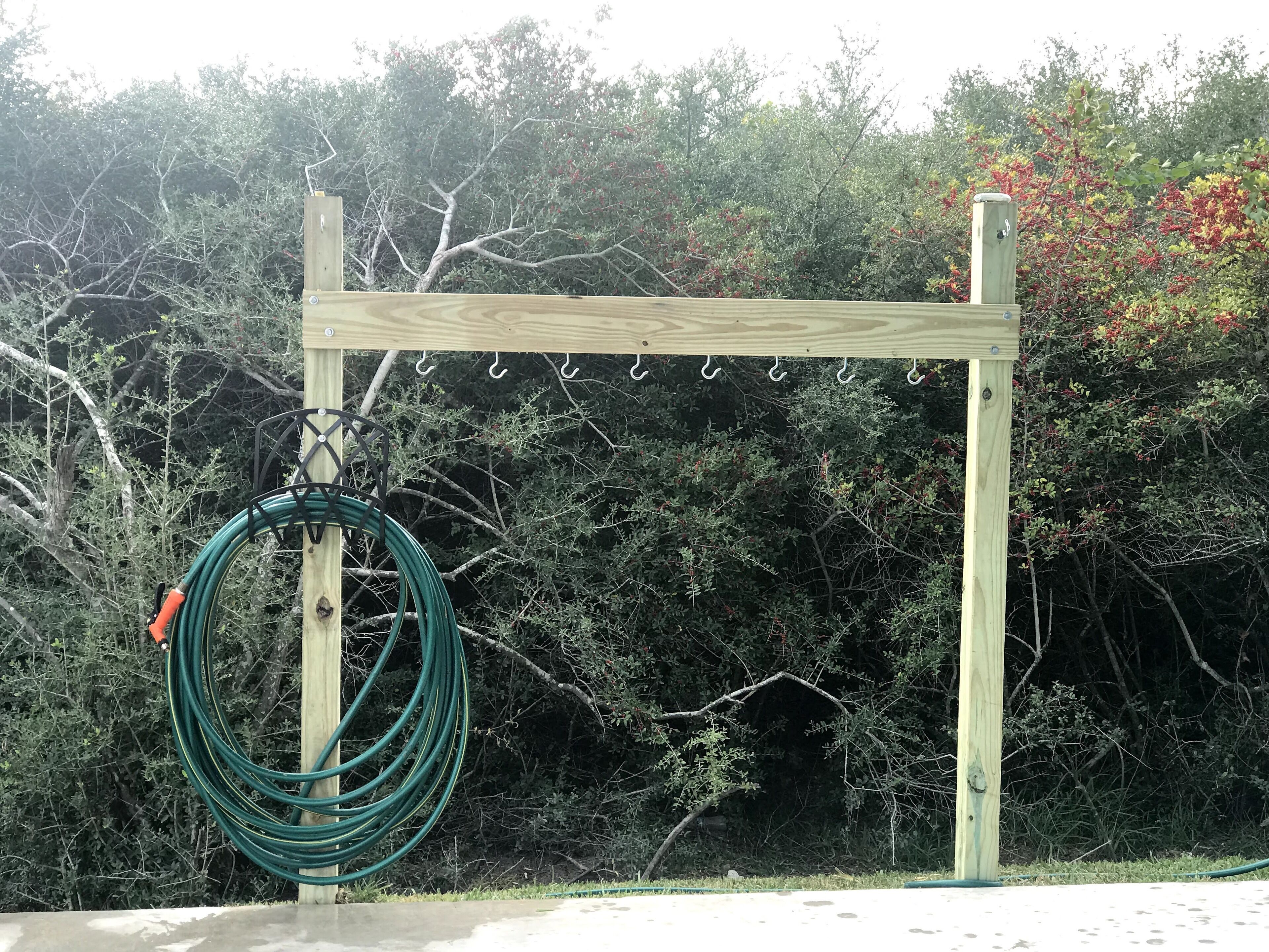 A wooden structure with a coiled garden hose and hooks.