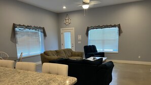 A spacious living room with a large dark blue sofa, a beige sofa, and a white chair. There is a granite countertop and a ceiling fan. - Perfect for fishermen and families for your stay in Port O'Connor! (Port O'Connor)
