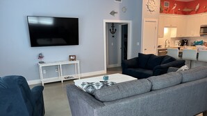 A living room with a grey sofa, a white coffee table, a TV, and a white console table with decorative items. - Perfect for fishermen and families for your stay in Port O'Connor! (Port O'Connor)