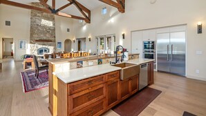Une cuisine spacieuse dotée d’un grand îlot central, de meubles en bois et d’une cheminée en pierre.