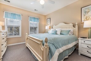 Un dormitorio con cama, cómoda, mesita de noche y ventilador de techo.