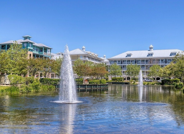 A fountain in a park with buildings in the background.