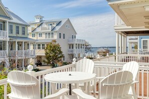 Propiedad costera con varias construcciones, una terraza con sillas blancas y vistas al mar.