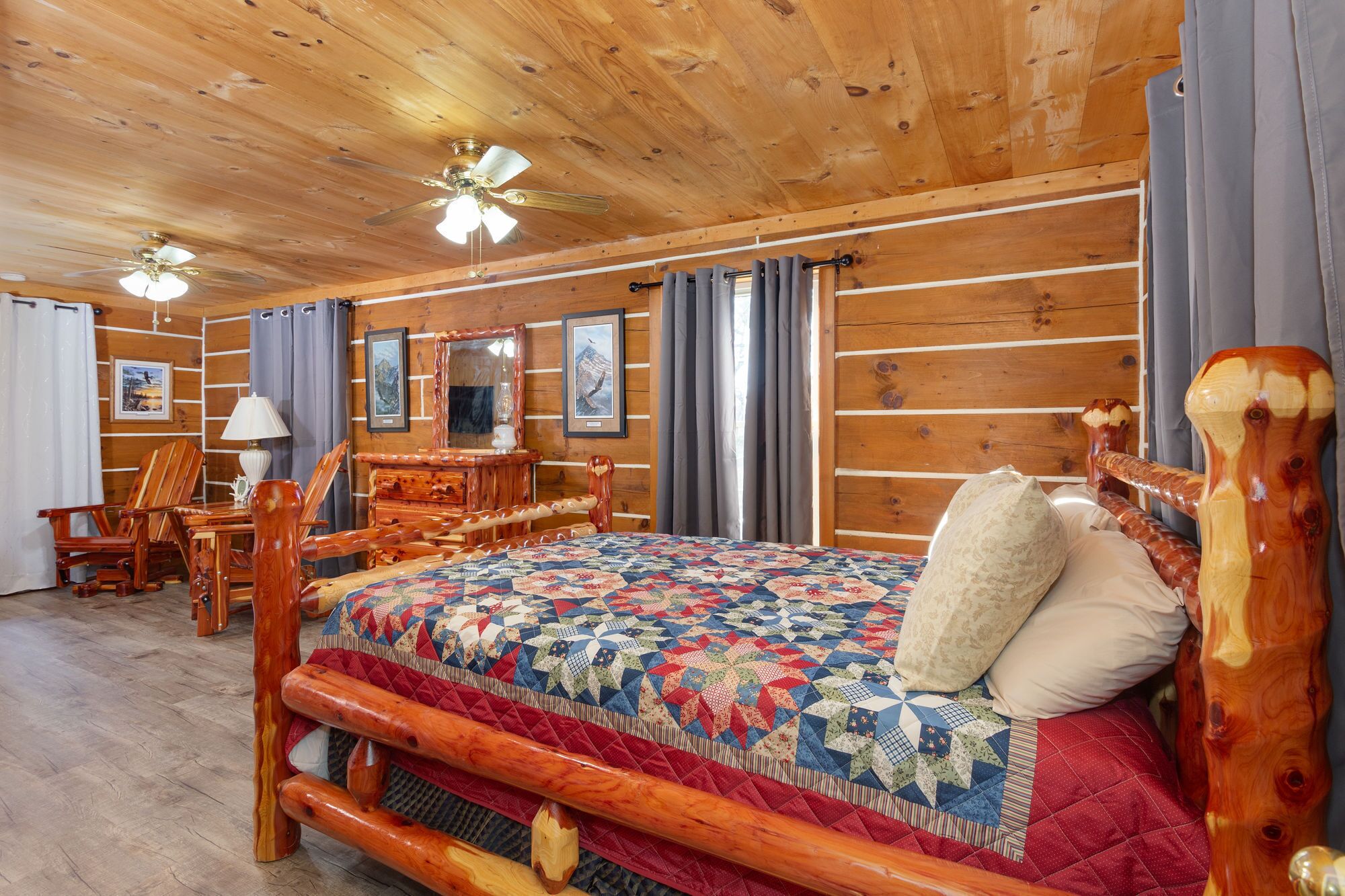 Une chambre de style rustique, avec un lit en bois, une commode en bois, une chaise et un ventilateur de plafond.