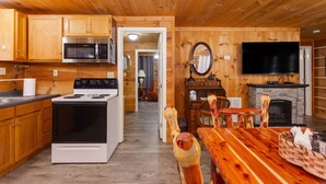 A wooden cabin interior with a kitchen, dining area, and fireplace. - Valentine Drive Cabin 2 (Lookout Mountain)