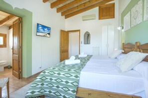 Un dormitorio con una cama, techo de madera, una ventana y una puerta.