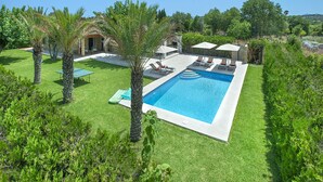 A swimming pool with a tiled deck, surrounded by palm trees and a well-maintained lawn. - VILLA  DIVINA - LUXURY RETREAT (Pollensa)