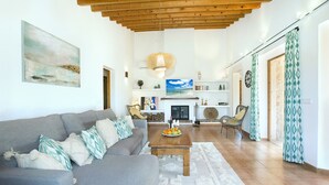 A living room with a grey sofa, a wooden coffee table, and a fireplace. - VILLA  DIVINA - LUXURY RETREAT (Pollensa)