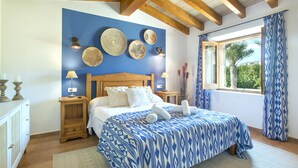 A bedroom with a bed, wooden headboard, bedside tables, wall decor, and a window with curtains. - VILLA  DIVINA - LUXURY RETREAT (Pollensa)