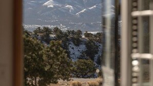 A room with a view of snow-capped mountains, a wooden deck, and a dining table. - Rhode's Hideaway- Dog Friendly, Minutes to Salida, Close to Monarch (Salida)