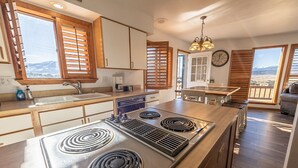 A kitchen with a central island stove, wooden cabinets, and a view of the mountains through the windows. - Rhode's Hideaway- Dog Friendly, Minutes to Salida, Close to Monarch (Salida)