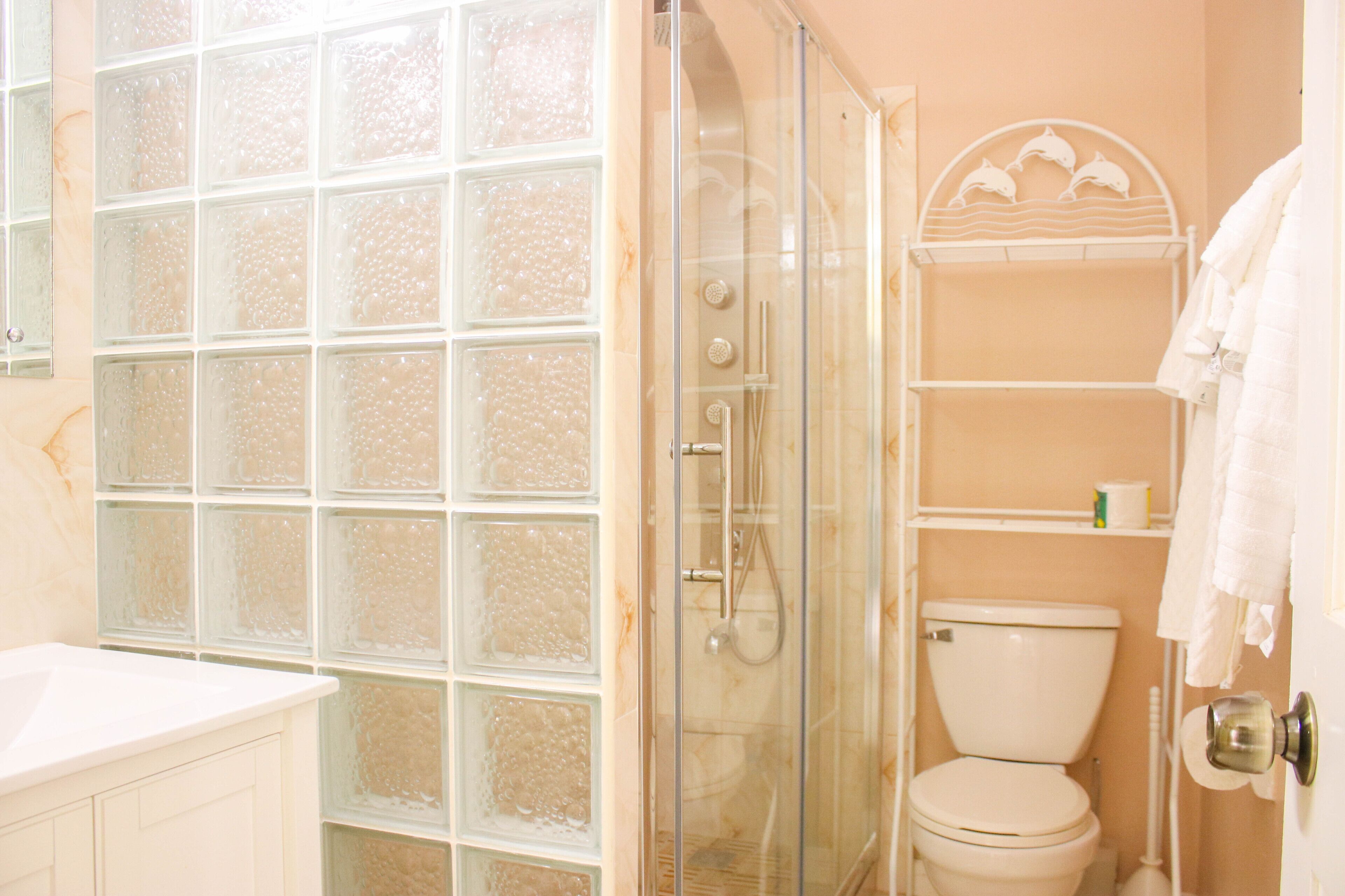A bathroom with a glass shower enclosure, a toilet, and a white sink.