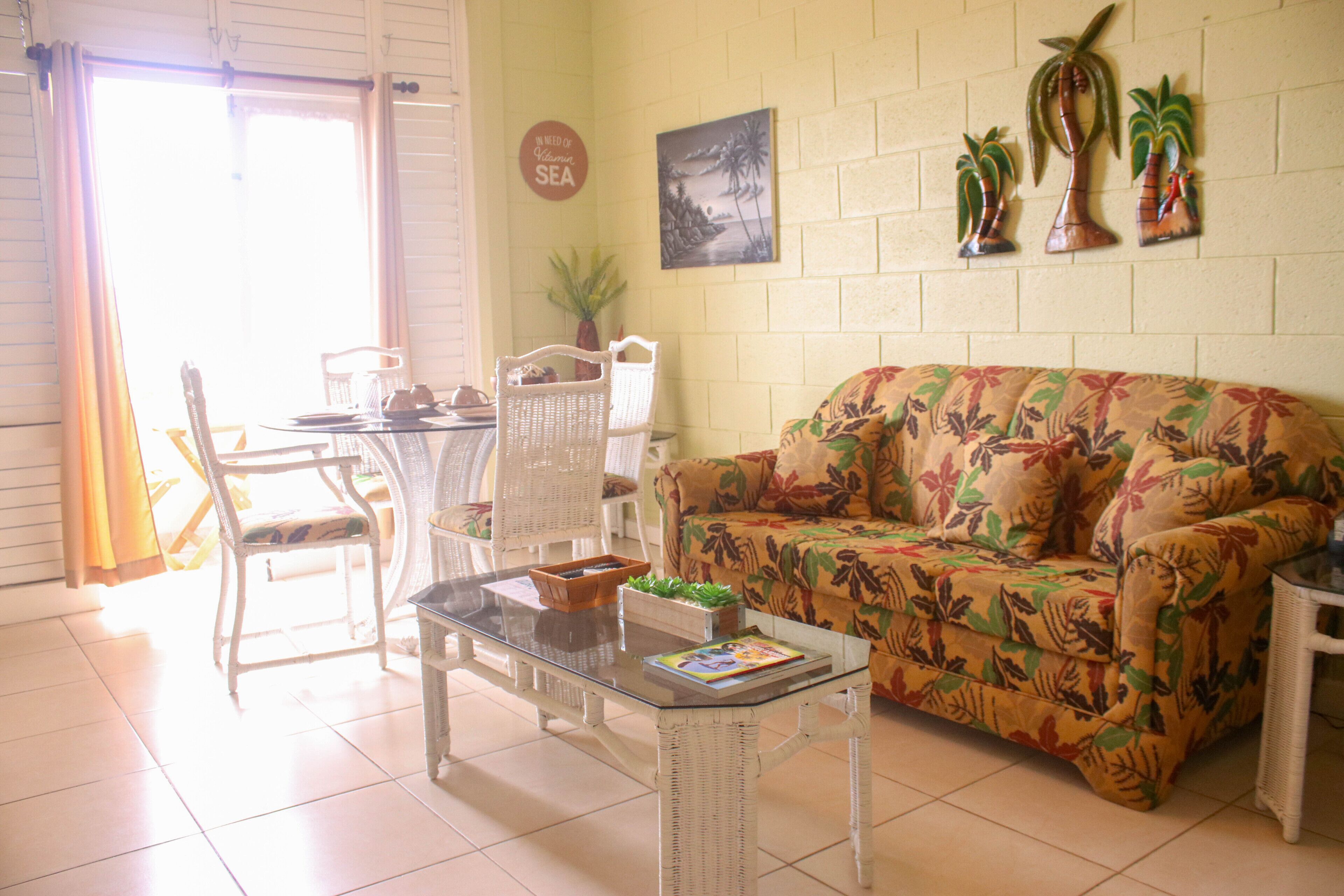A living room with a sofa, chairs, a glass coffee table, and a dining table.