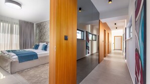 Een moderne hotelkamer met een bed, een badkamer en een gang met kunstwerken.