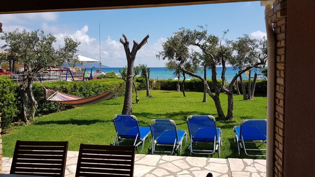 Une terrasse avec un sol en pierre, une vue sur la mer et plusieurs fauteuils bleus.