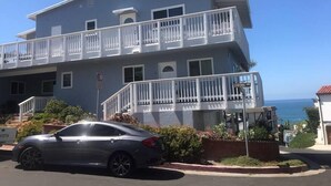 A two-story building with balconies, a Toyota sign, and a view of the ocean. - Yard, Dog, & Kid Friendly! -Blue Whale Inn #C (San Clemente)