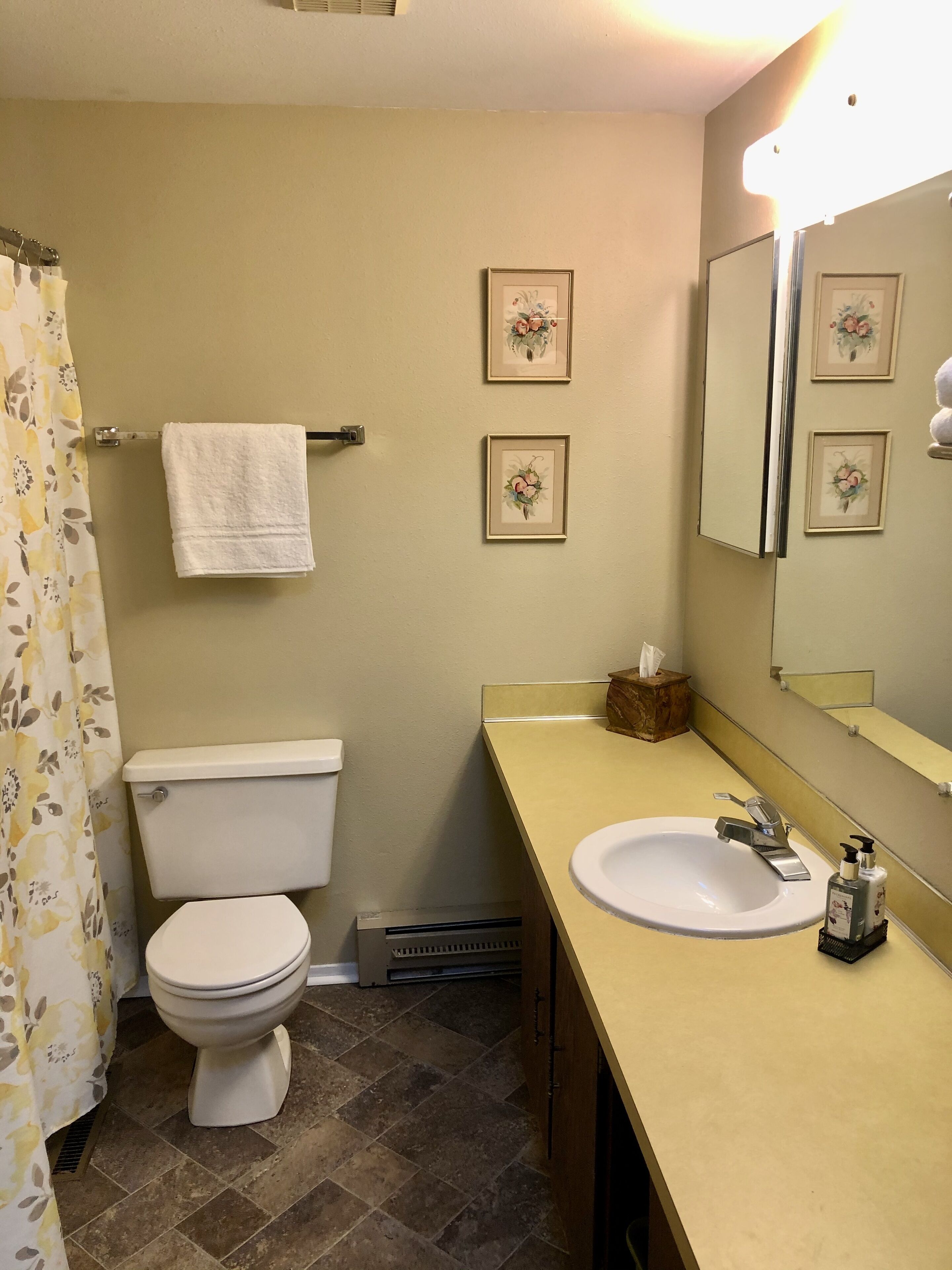 Un baño con inodoro, lavamanos y cortina de ducha.